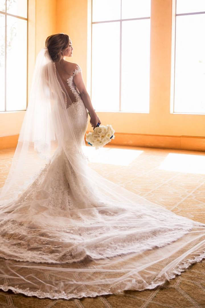 two tier long cathedral wedding veil with lace edges over bride's low updo