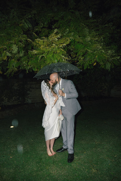 calf length mantilla bridal veil in French lace on bride and groom in rain