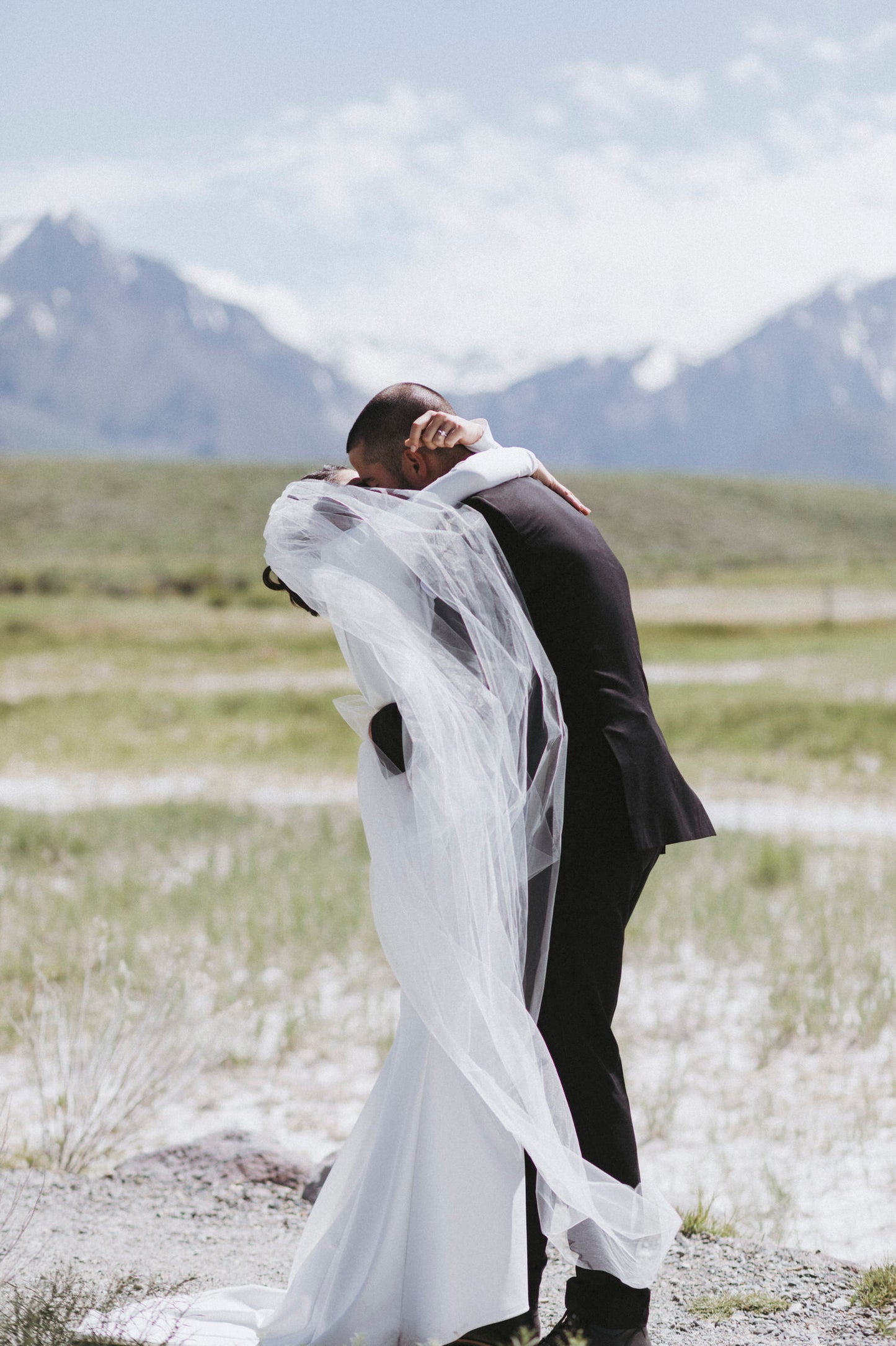 romantic thin white wedding veil encircling bride and groom for mountain prairie wedding