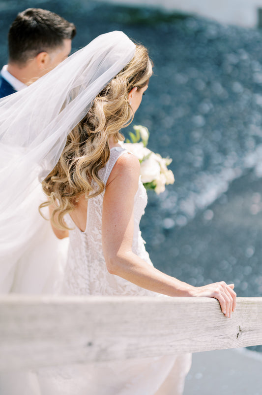 bride walking down stairs to beach with curled hair and silk bridal veil