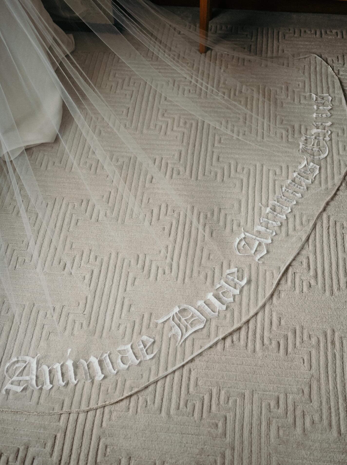 gothic script embroidered phrase on bottom of long cathedral length bridal veil