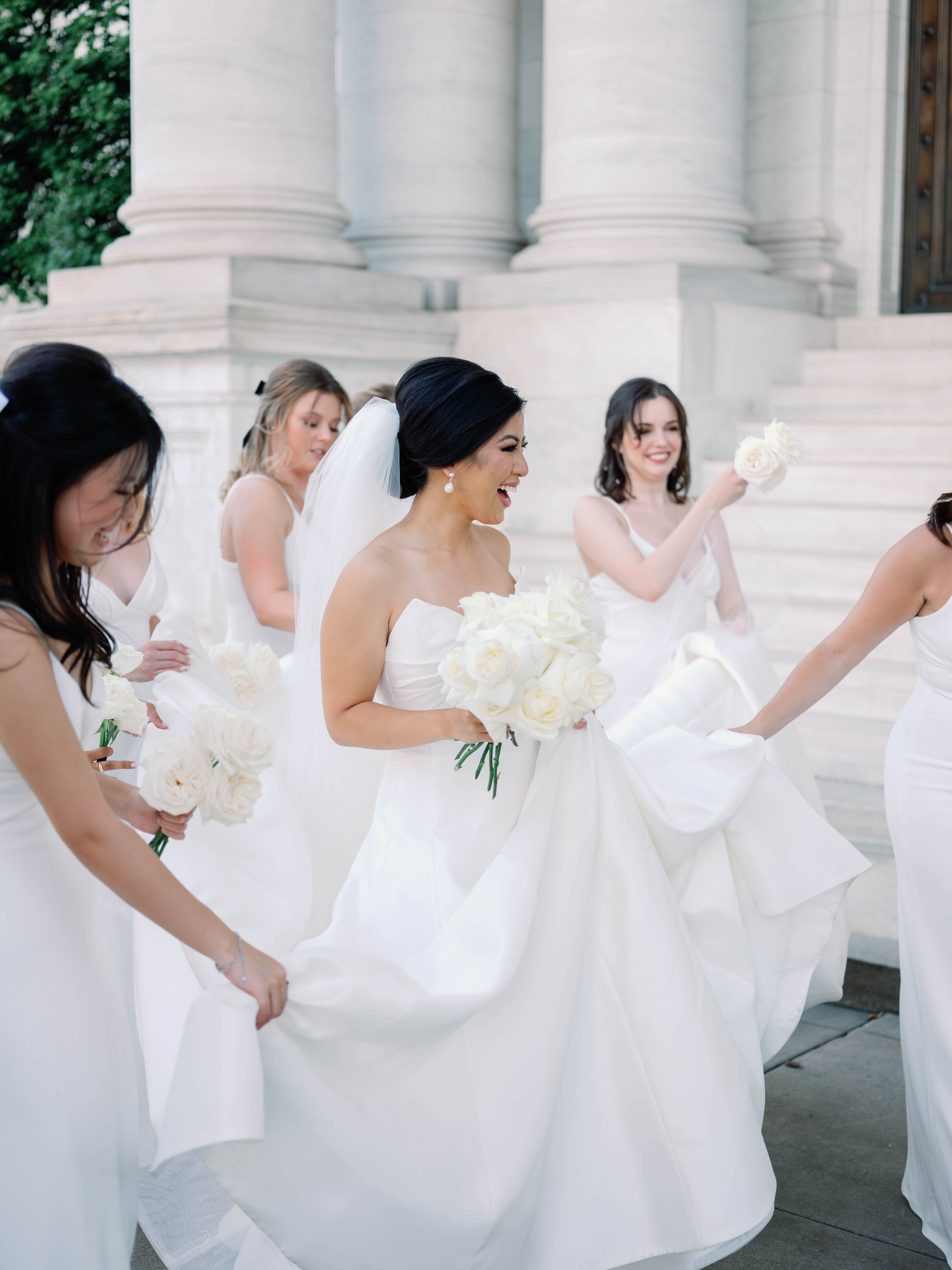 bride in white structured ballgown with extra full and puffy cathedral wedding veil over low bun as bridesmaids carry her bridal veil