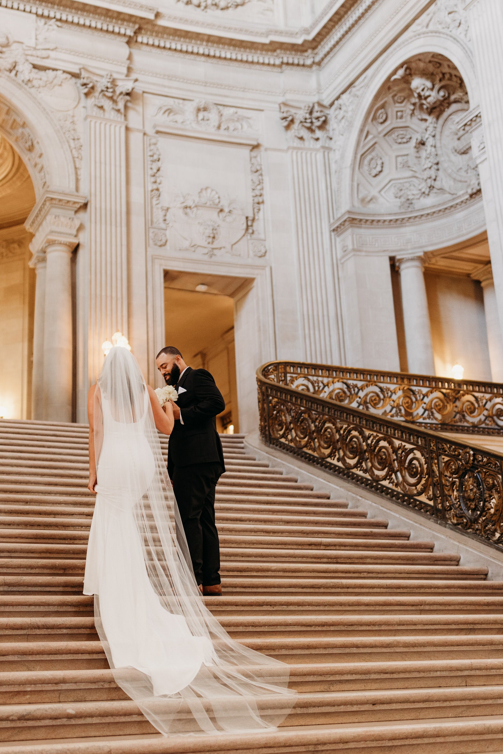 regal cathedral length bridal veil with raw edge and simple scoop back gown on bride going up staircase