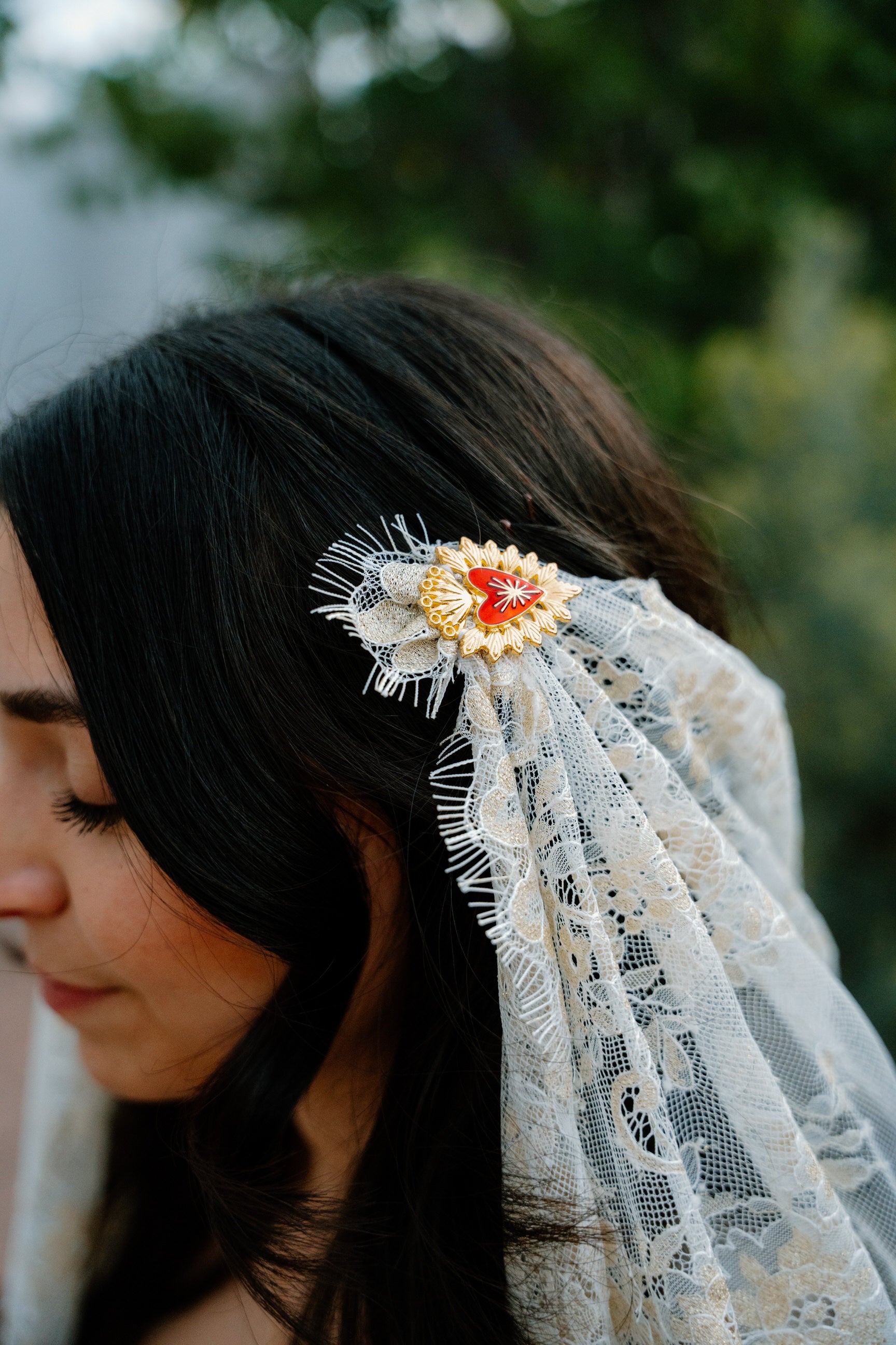 bride wearing a lace draped veil headpiece with a gold hairpin detail outdoors