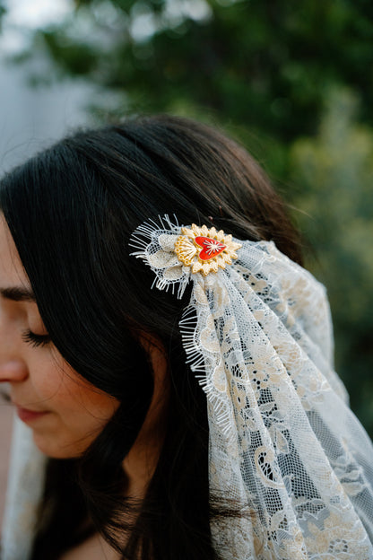 bride wearing a lace draped veil headpiece with a gold hairpin detail outdoors