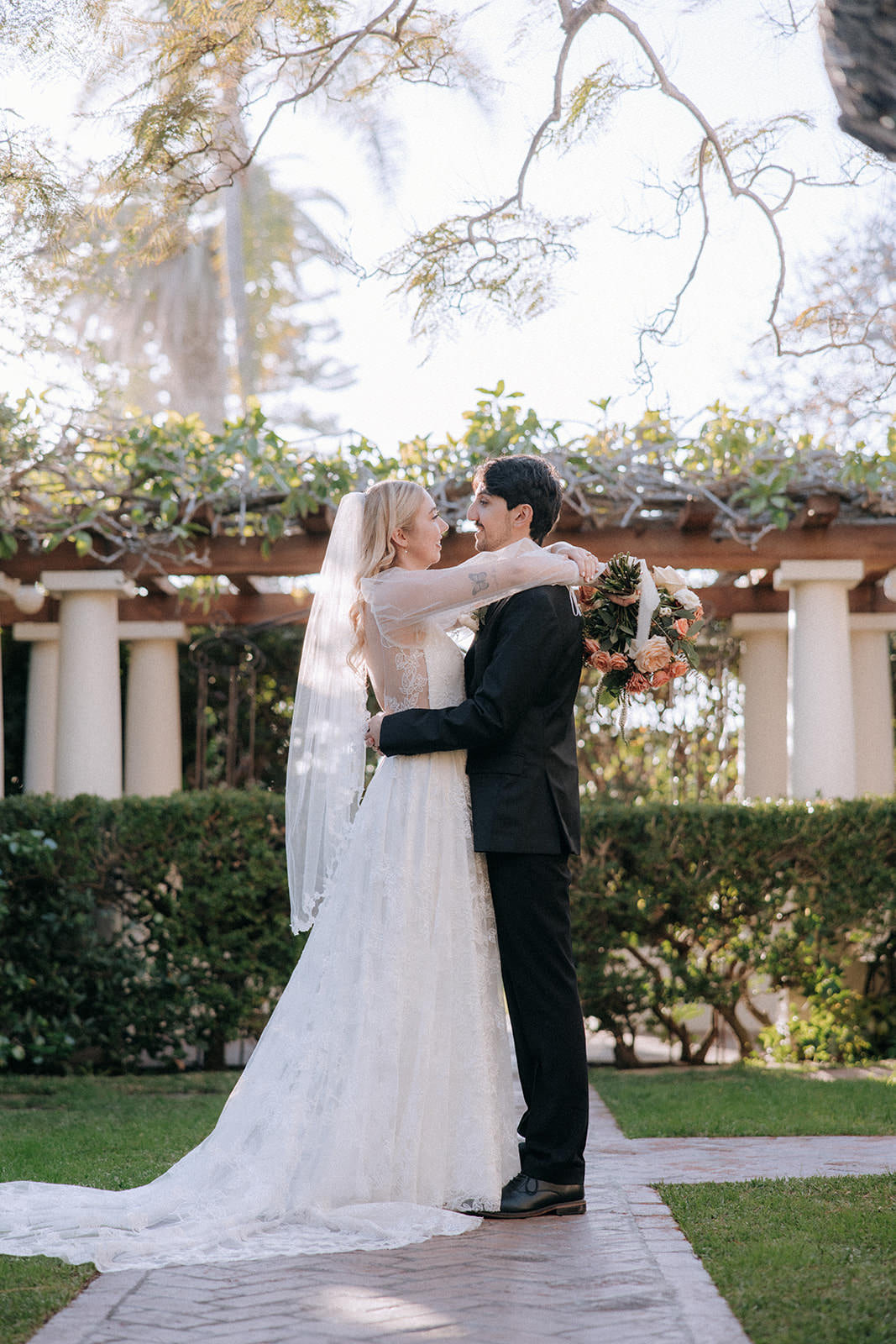 white puff sleeve wedding dress on bride wearing a white fingertip leaf veil embracing groom