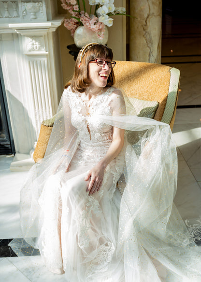 gold and ivory sheer bridal cape with metallic stars and moons on a bride wearing a celestial wedding crown