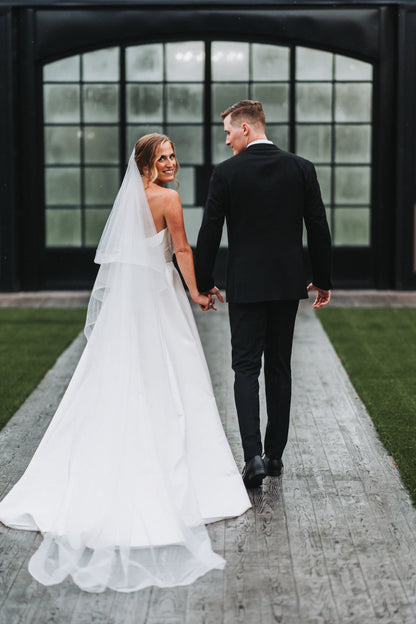 bride and groom holding hands on a pathway with a long horsehair bridal veil with blusher
