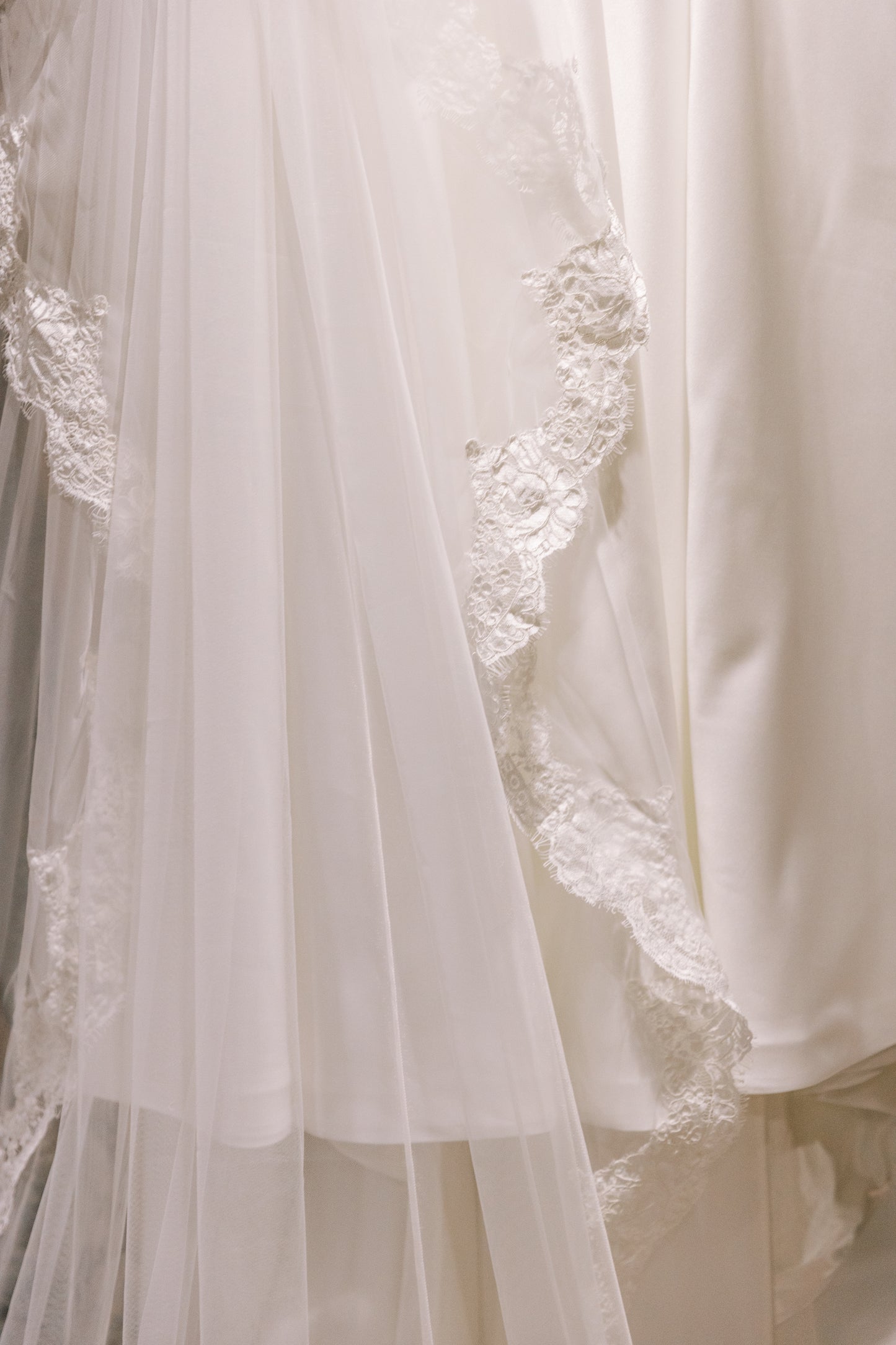 Close-up of an ivory lace wedding veil with tulle and French corded scallop lace trim