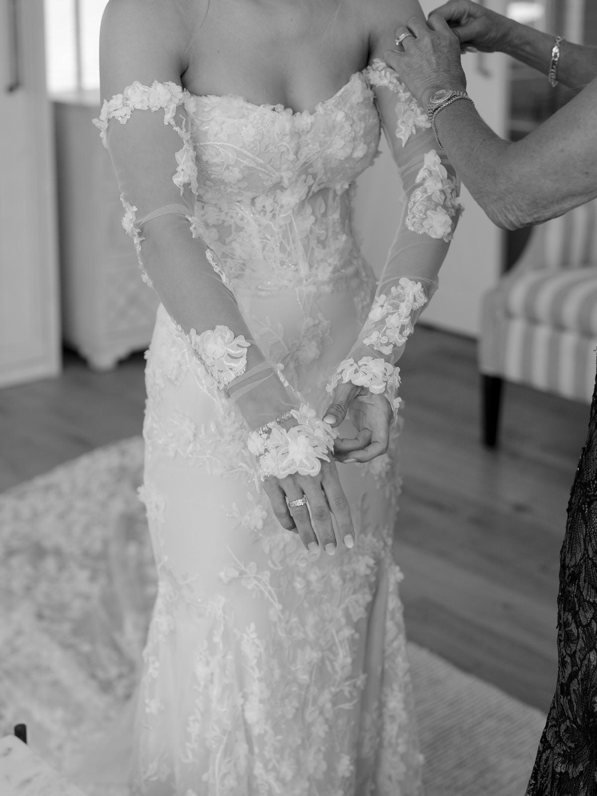 Bride wearing a floral wedding dress putting on fingerless wedding gloves with matching embroidery 