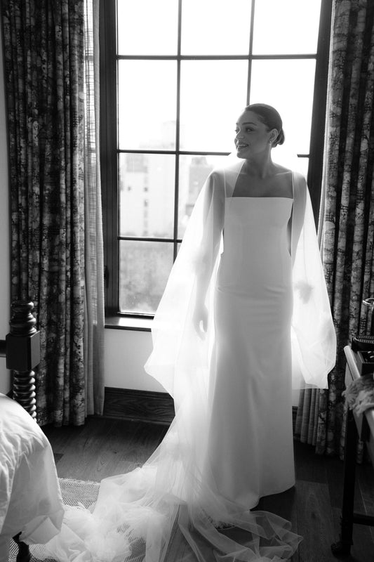 romantic long cathedral veil with oversized tulle flowers and bride wearing simple sheath spaghetti strap dress