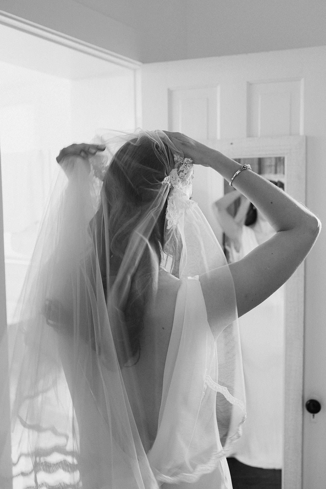 Bride adjusting a handmade Juliet cap vintage wedding veil in front of a mirror.