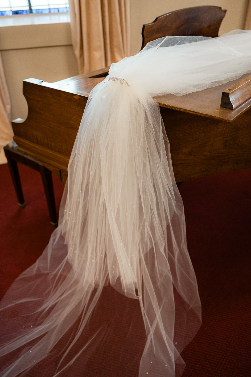 layered wedding veil draped over a piano with scattered sparkles and pearls
