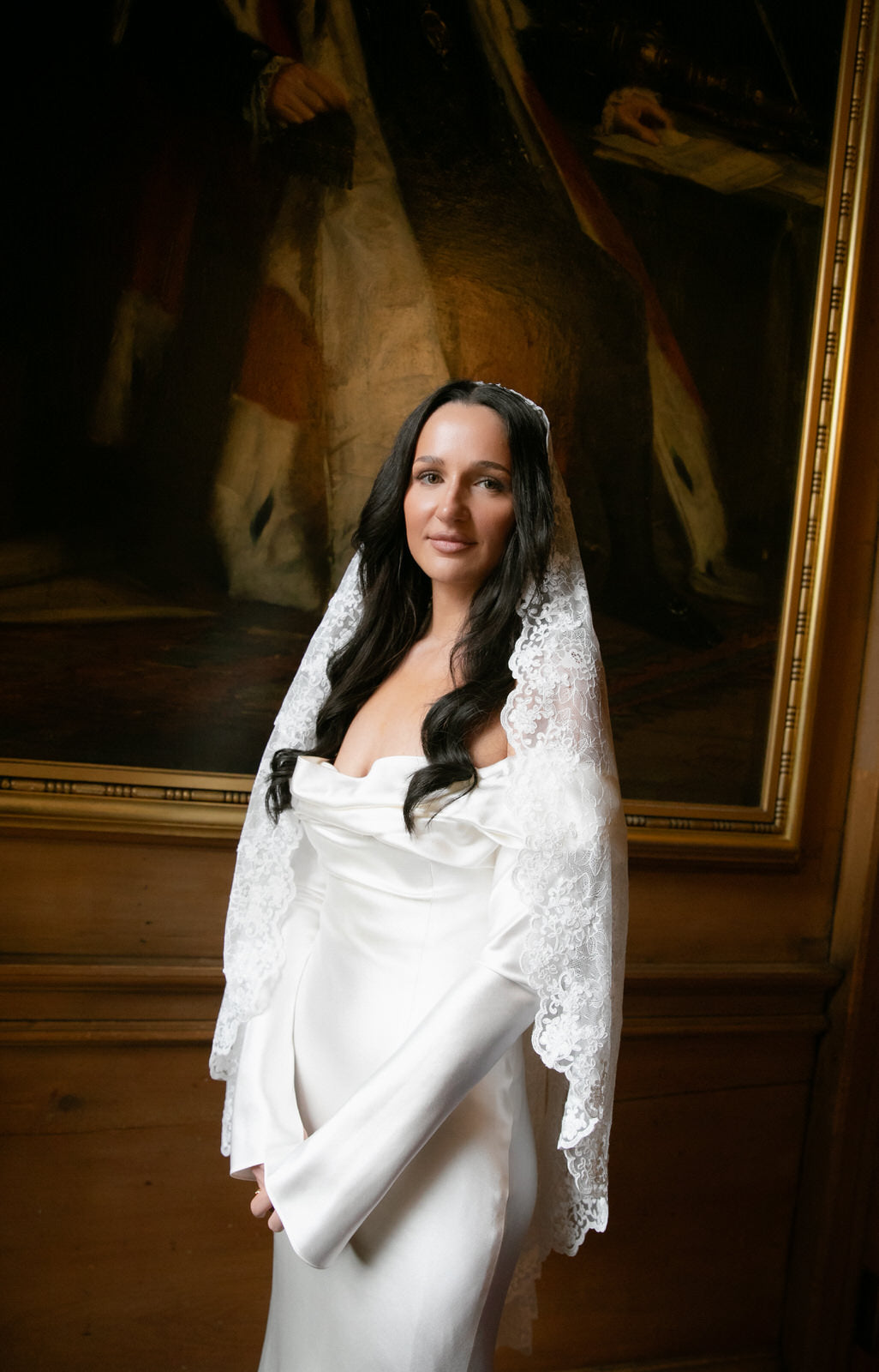 classic off shoulder sleeved satin wedding dress on bride n in a mantilla lace French wedding veil with loose down hair