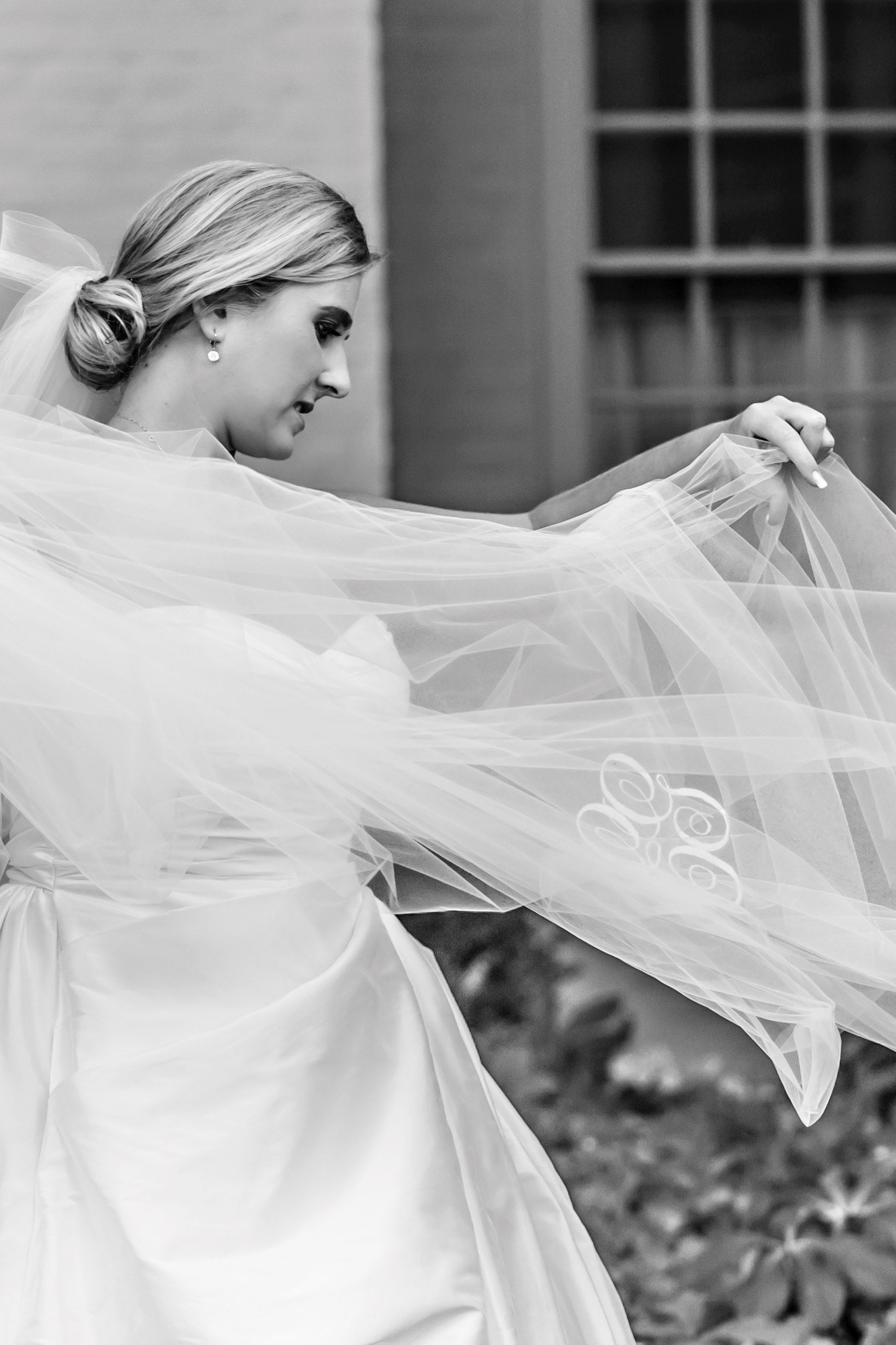 elegant formal bride holding long embroidered cathedral length wedding veil with custom initials embroidered on bottom