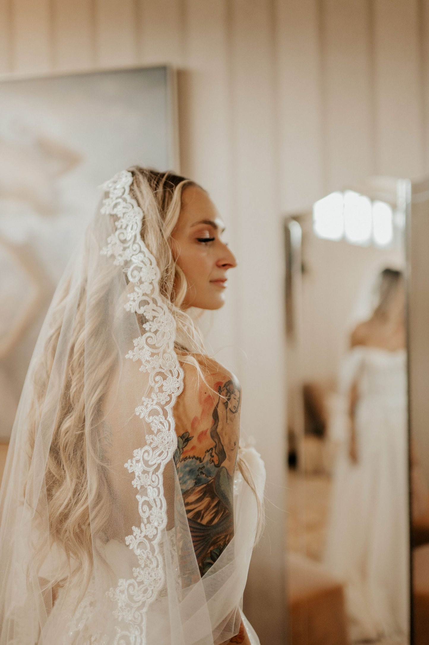 bride getting ready in mantilla light ivory bridal veil with colorful tattoo and draped off the shoulder sleeves