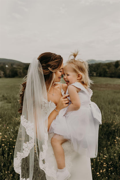 romantic swirl lace semi embroidered bridal veil in half up half down hairstyle on bride holding flower girl