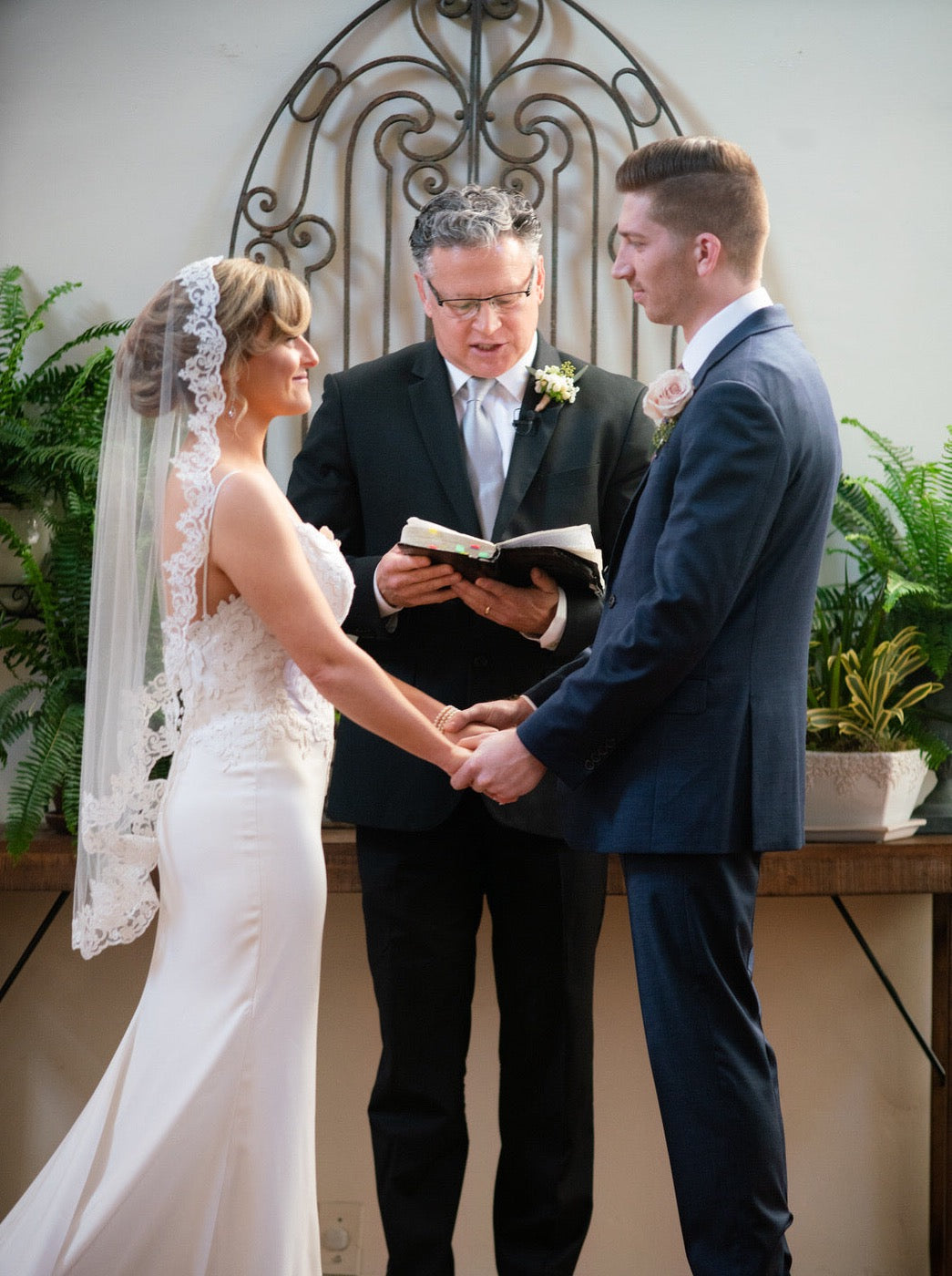 bride holding hands with groom at alter in mantilla fingertip length ivory bridal veil